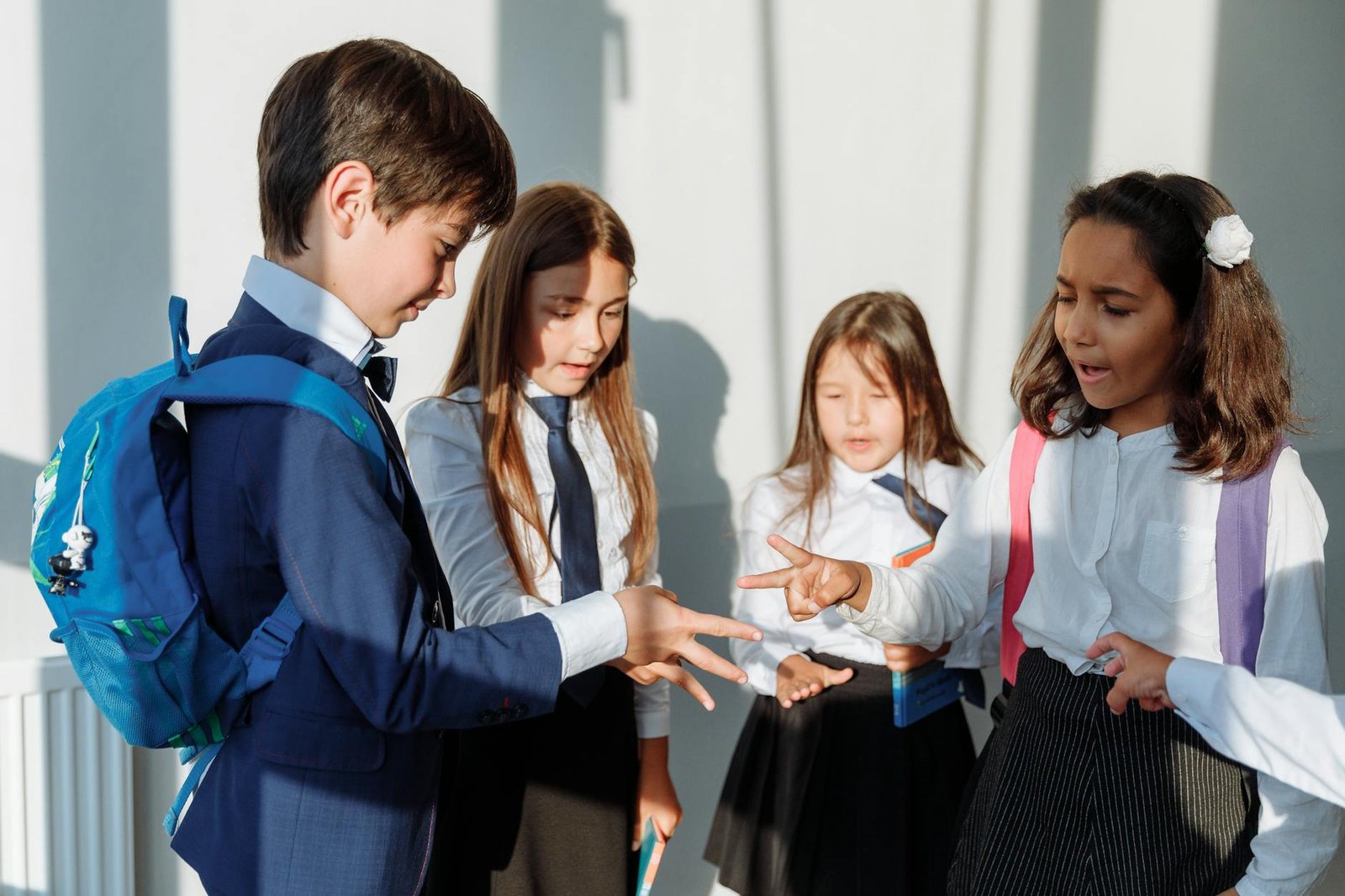 children in school uniform playing rock paper scissors