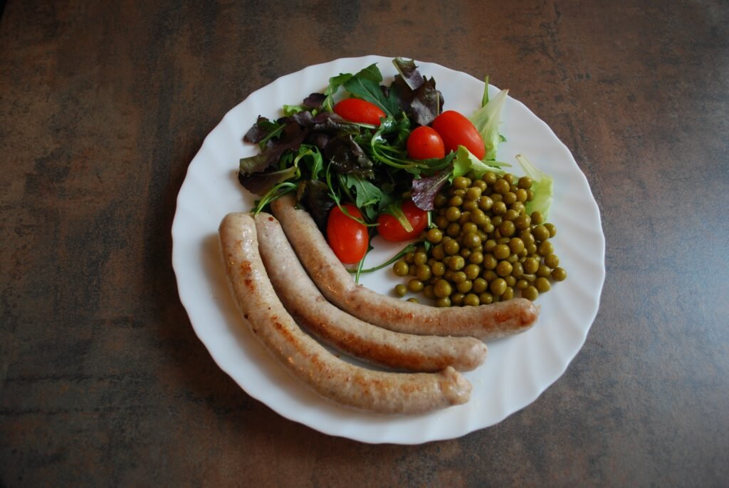 Roasted sausage and vegetables on a baking tray with herbs
