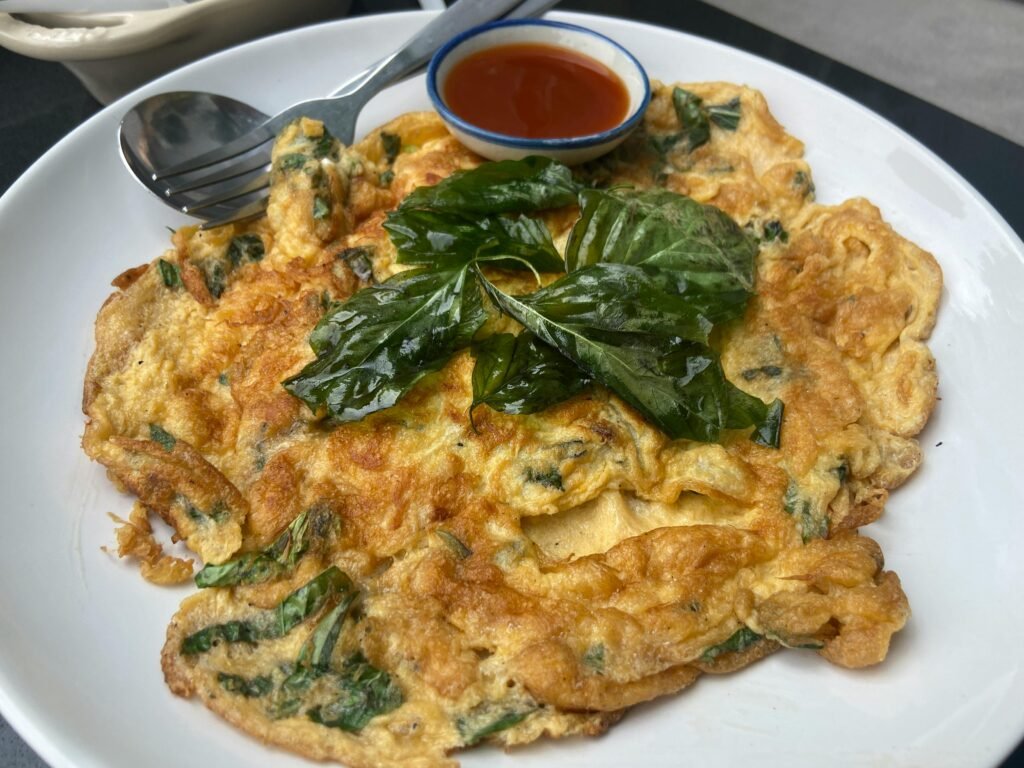 Fluffy Thai omelette with crisp edges served alongside rice.